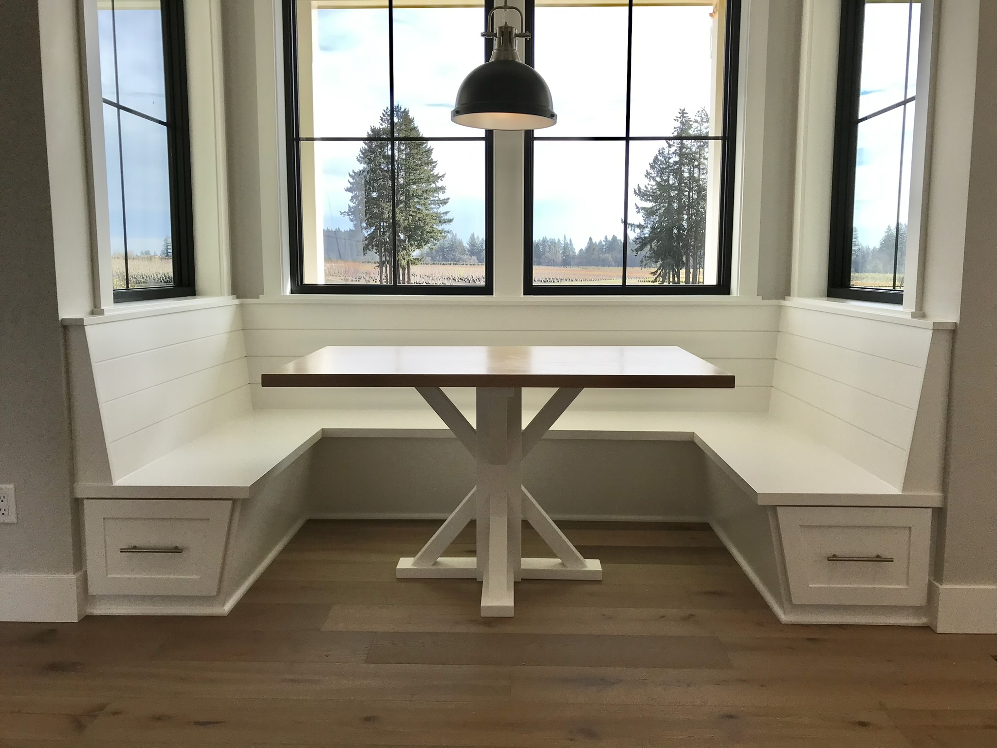 Built-in banquette bench seating with under-seat storage, shiplap backing, and matching pedestal table