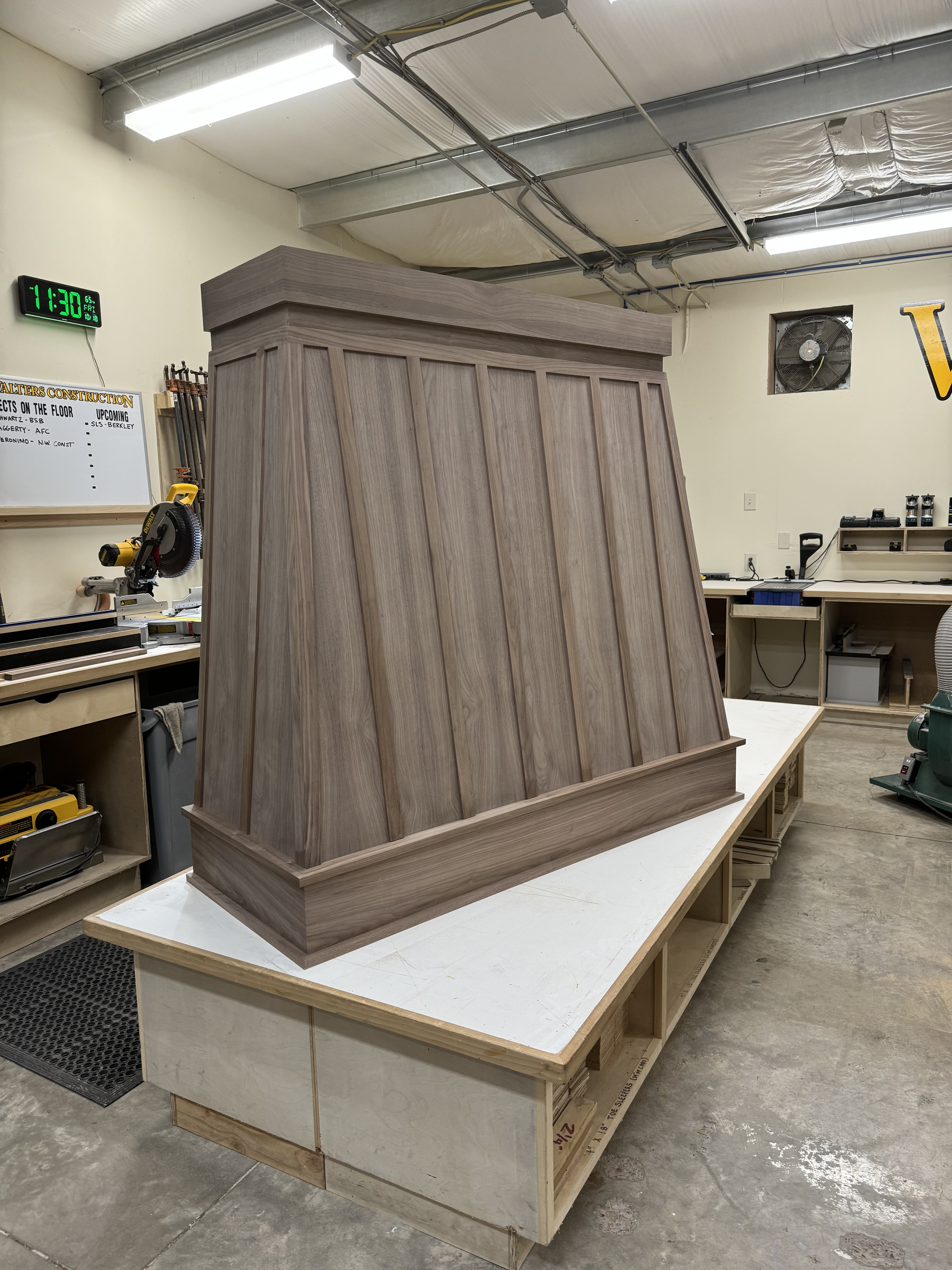 Custom wood-panel range hood with dark stain being built in the shop