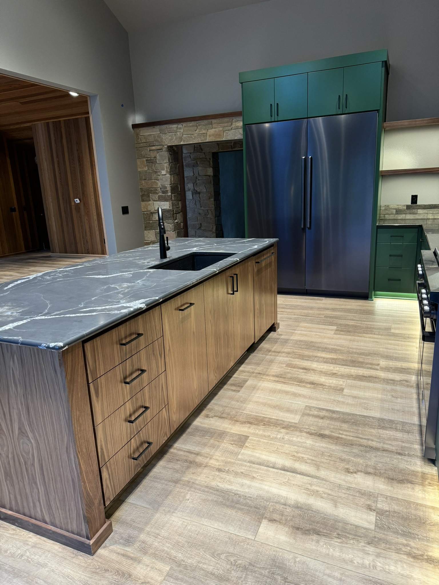 Custom walnut range hood and upper cabinet detail with gray-green lowers