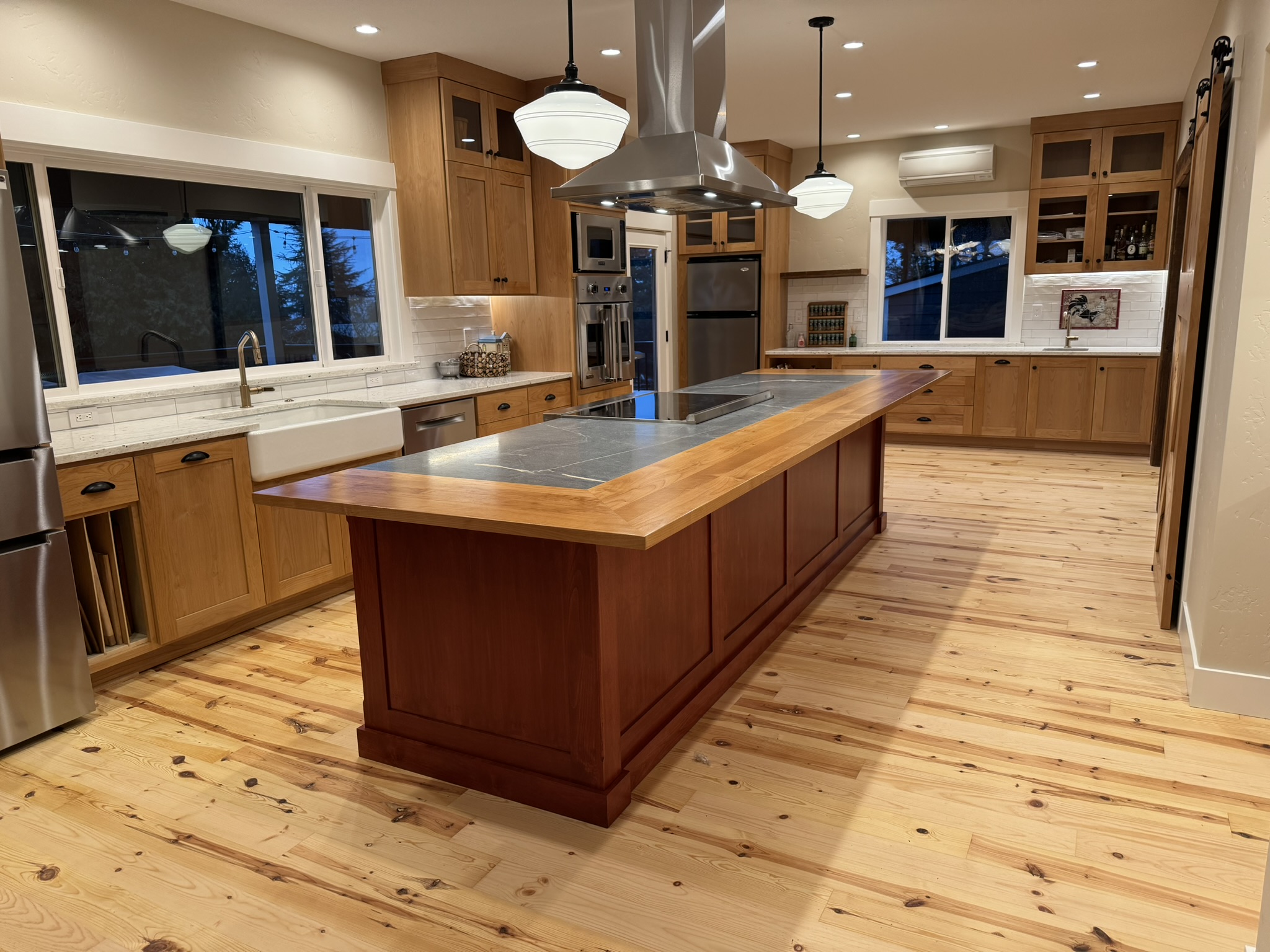 Warm stained wood kitchen with soapstone countertops and a large butcher block island