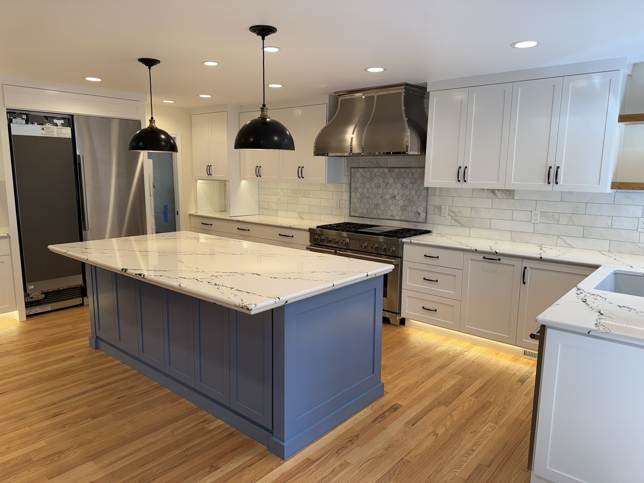 Full kitchen layout with blue island, white perimeter cabinetry, and iridescent tile bar wall
