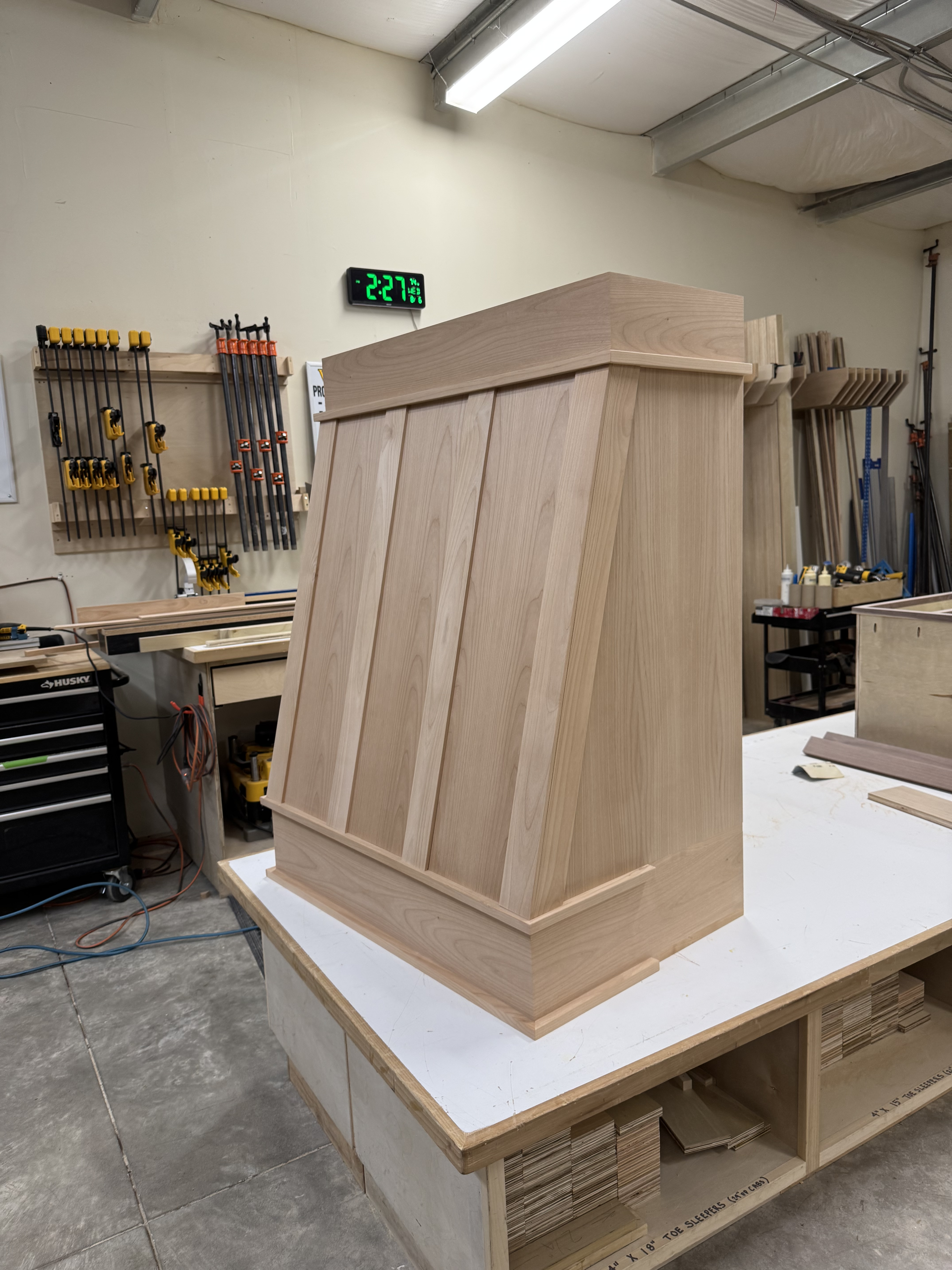 Natural oak range hood with arched panel detail under construction in the shop