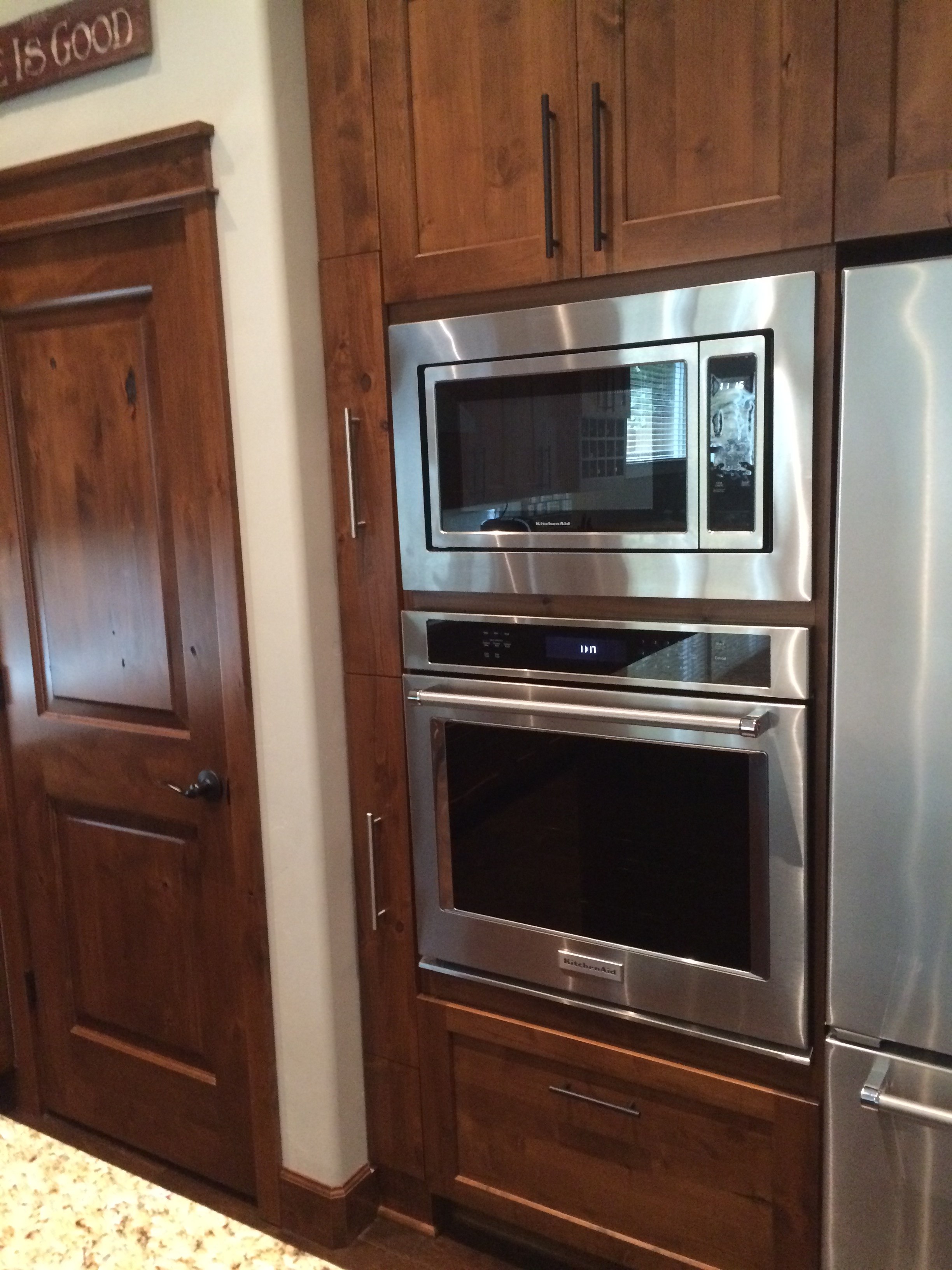 Warm wood kitchen appliance wall with integrated wall ovens and full-height refrigerator panel