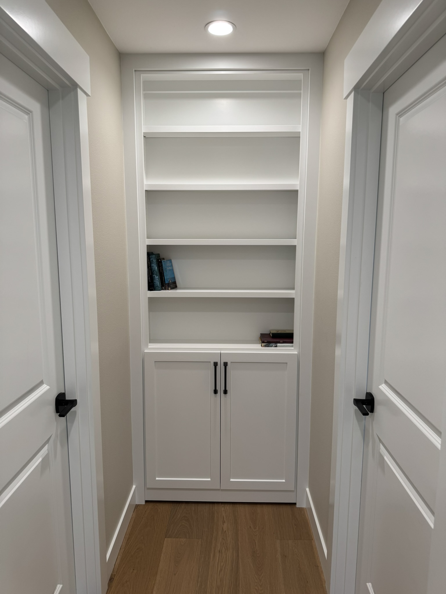 Floor-to-ceiling built-in bookcase in a hallway — concealing a hidden room door with no visible hardware