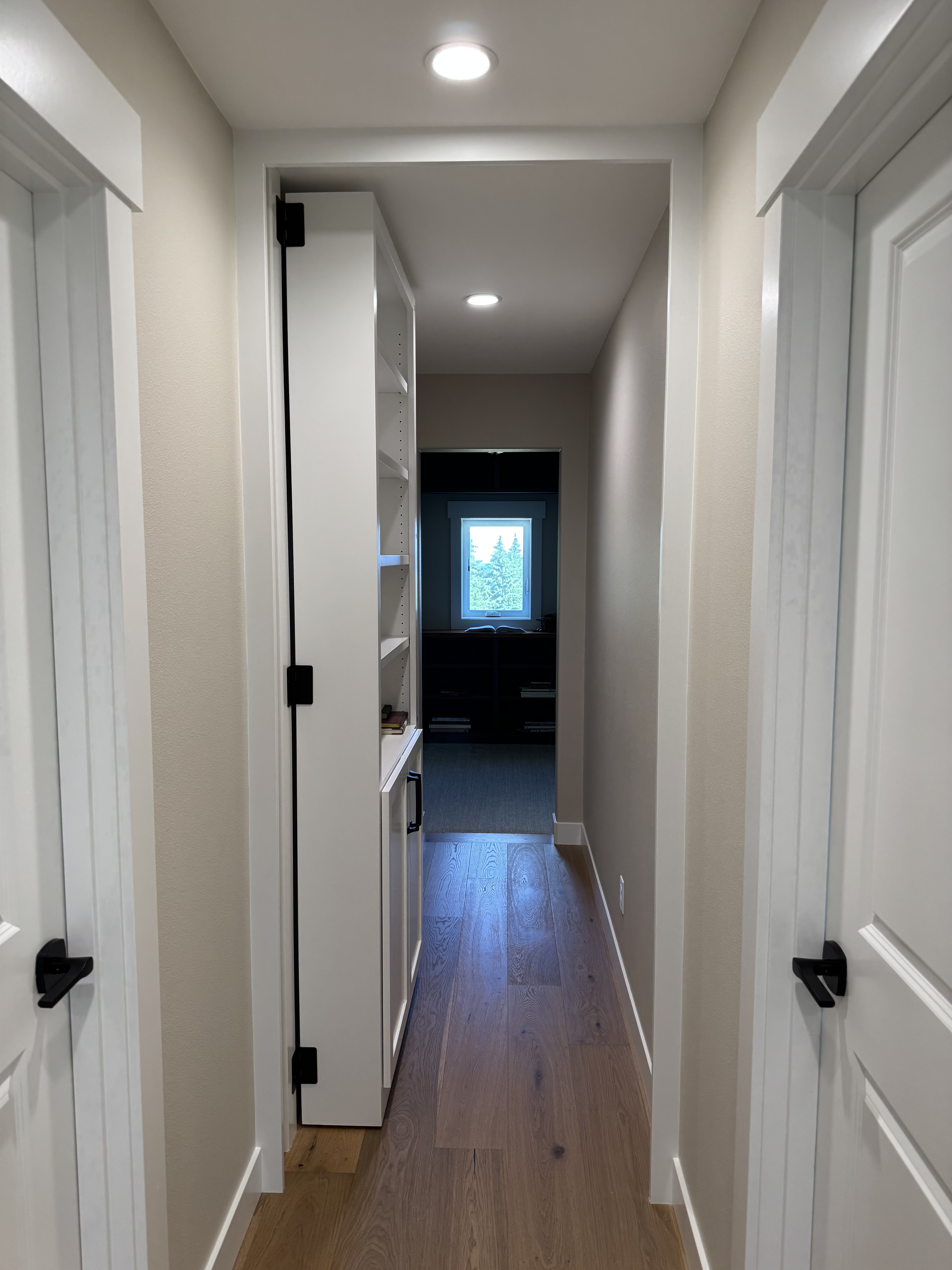 The bookcase door swung open on concealed pivot hardware, revealing the hidden room behind it