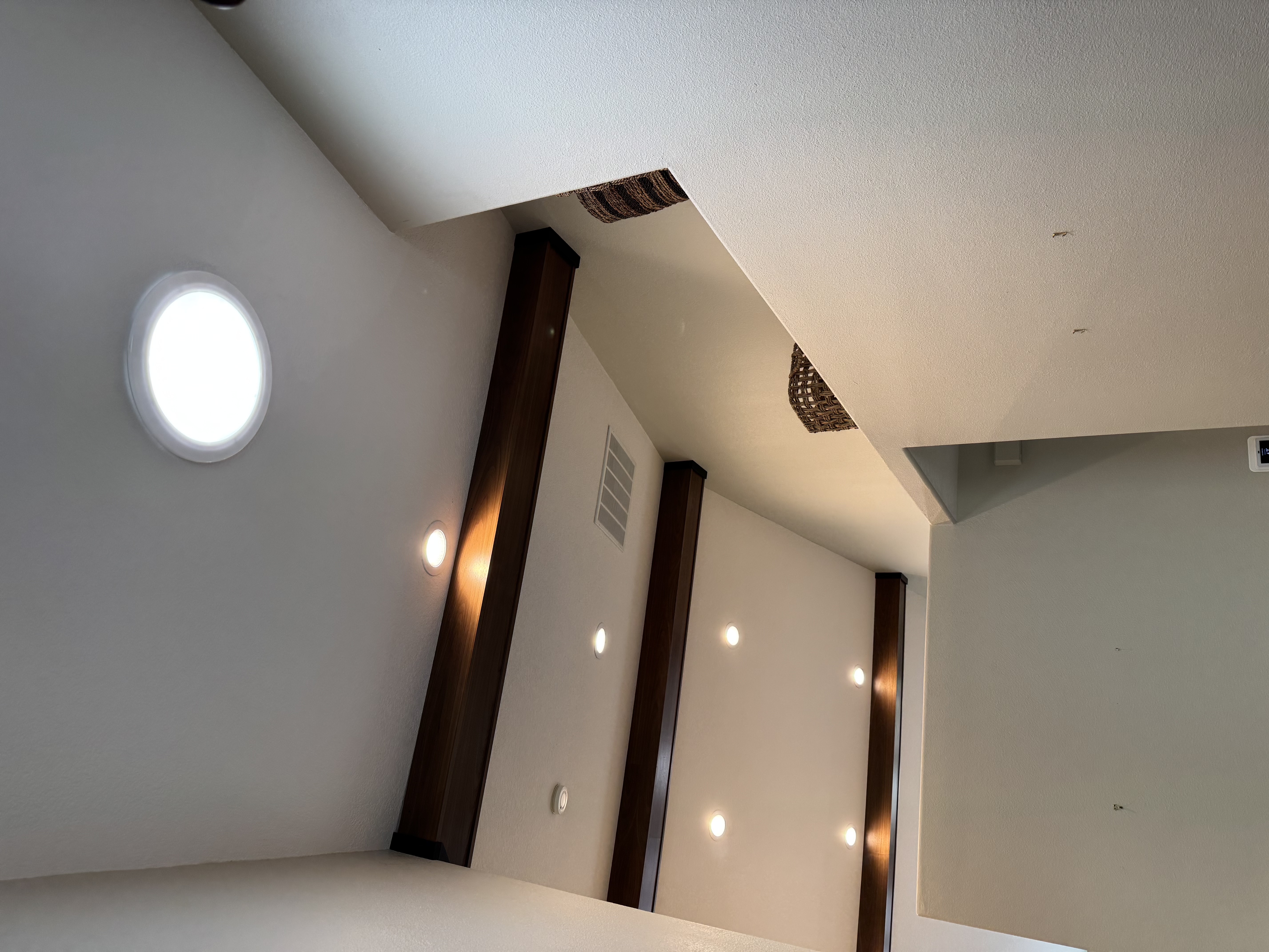 Walnut faux beams on a vaulted ceiling with porthole window and integrated lighting