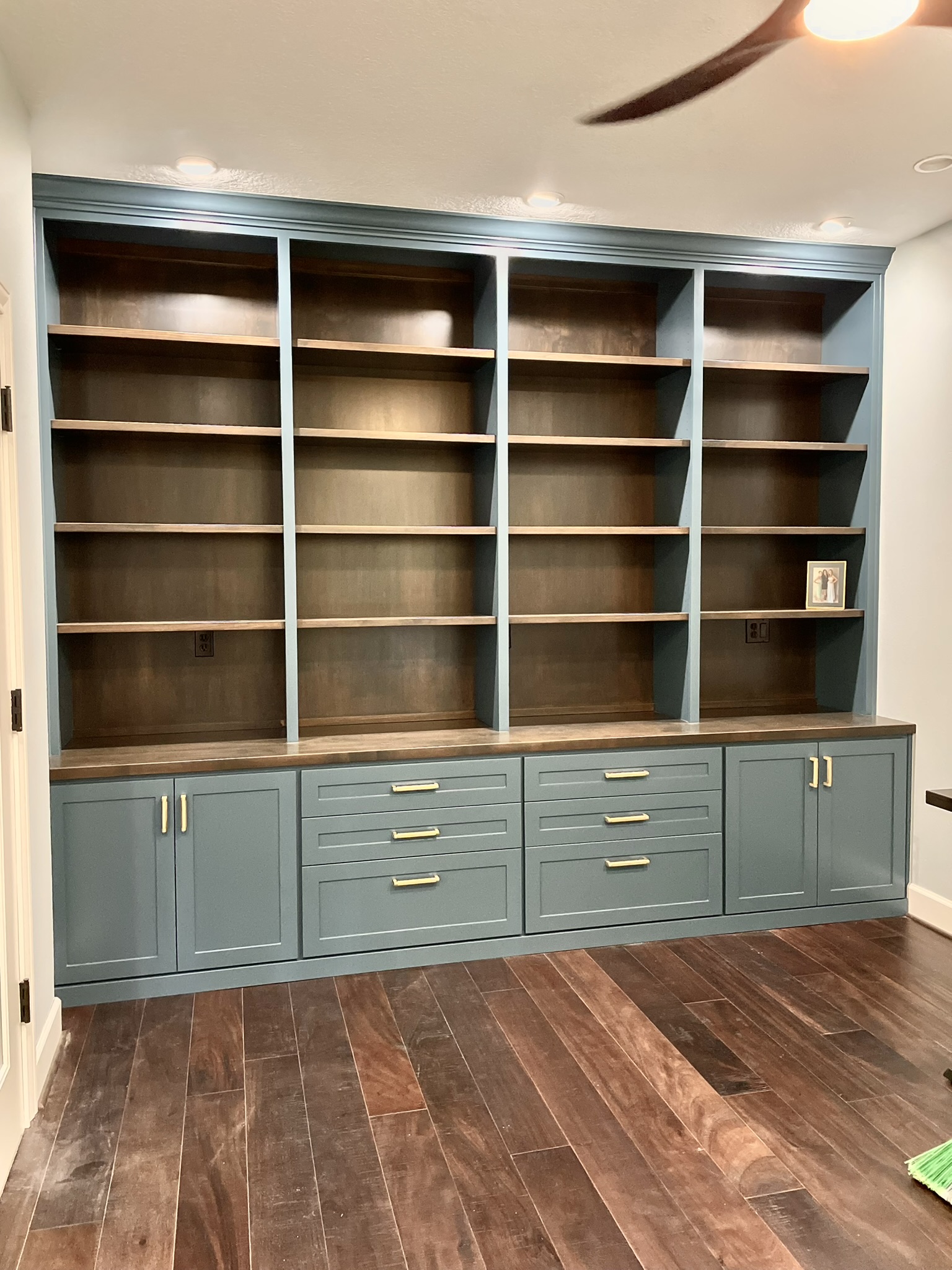 Teal built-in library with walnut interiors and brass hardware