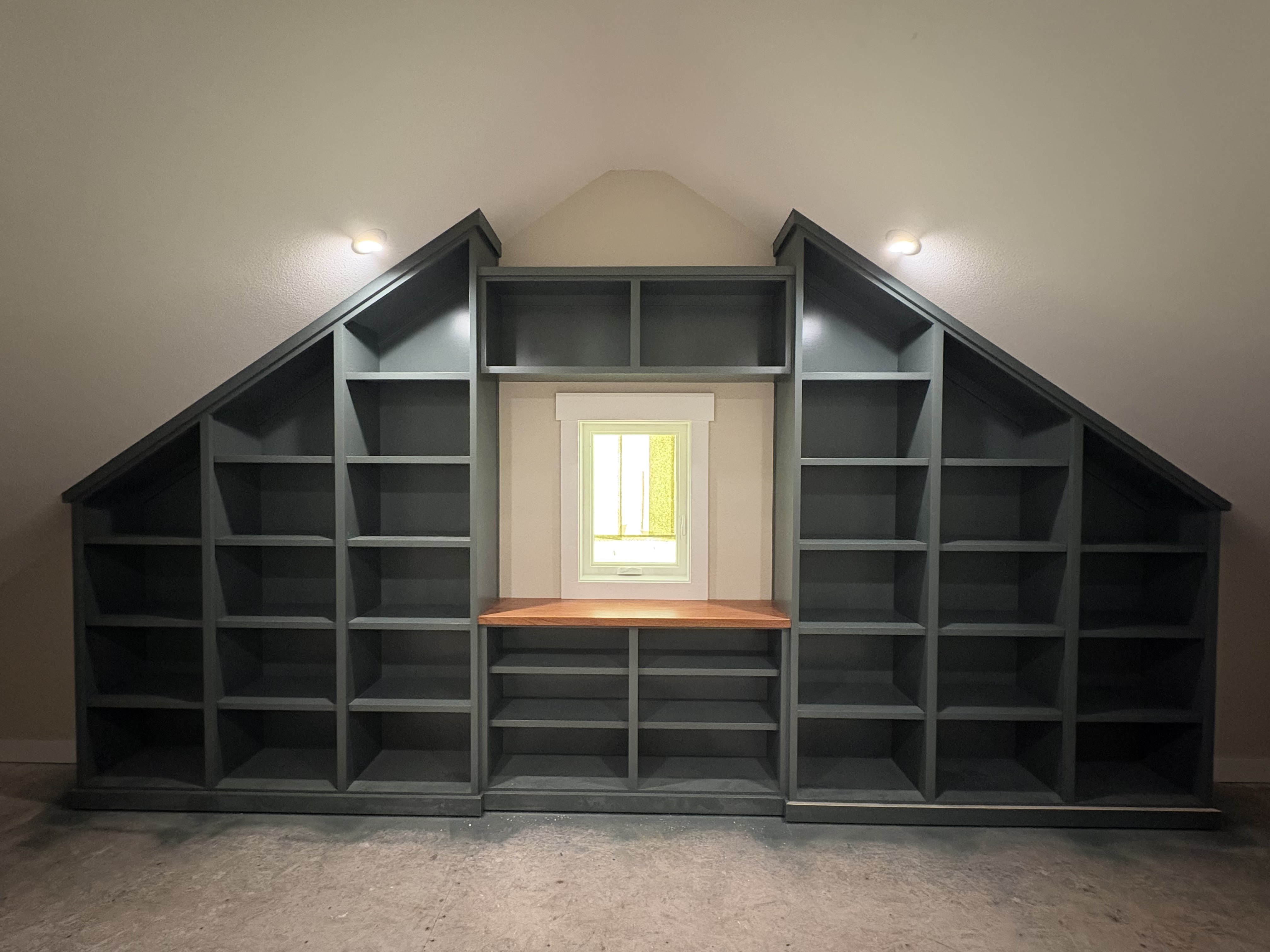 Dark charcoal painted floor-to-ceiling built-in bookcase wrapping an angled wall, concealing a hidden room door