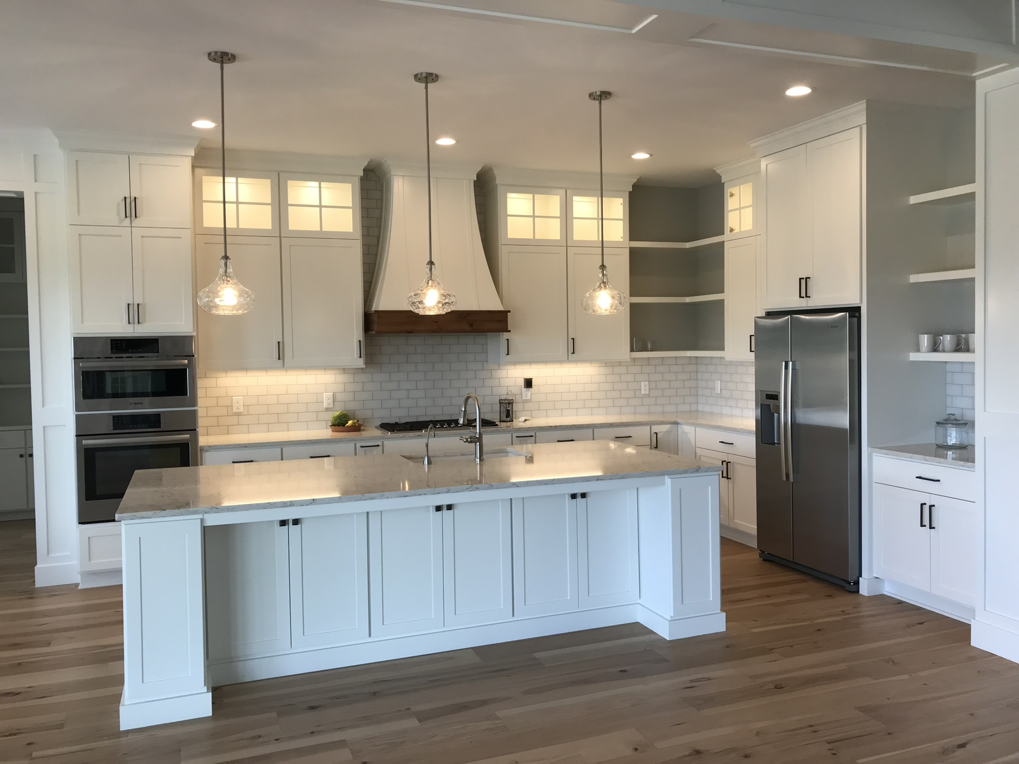 Classic white inset kitchen with glass-front uppers and wood-accent hood