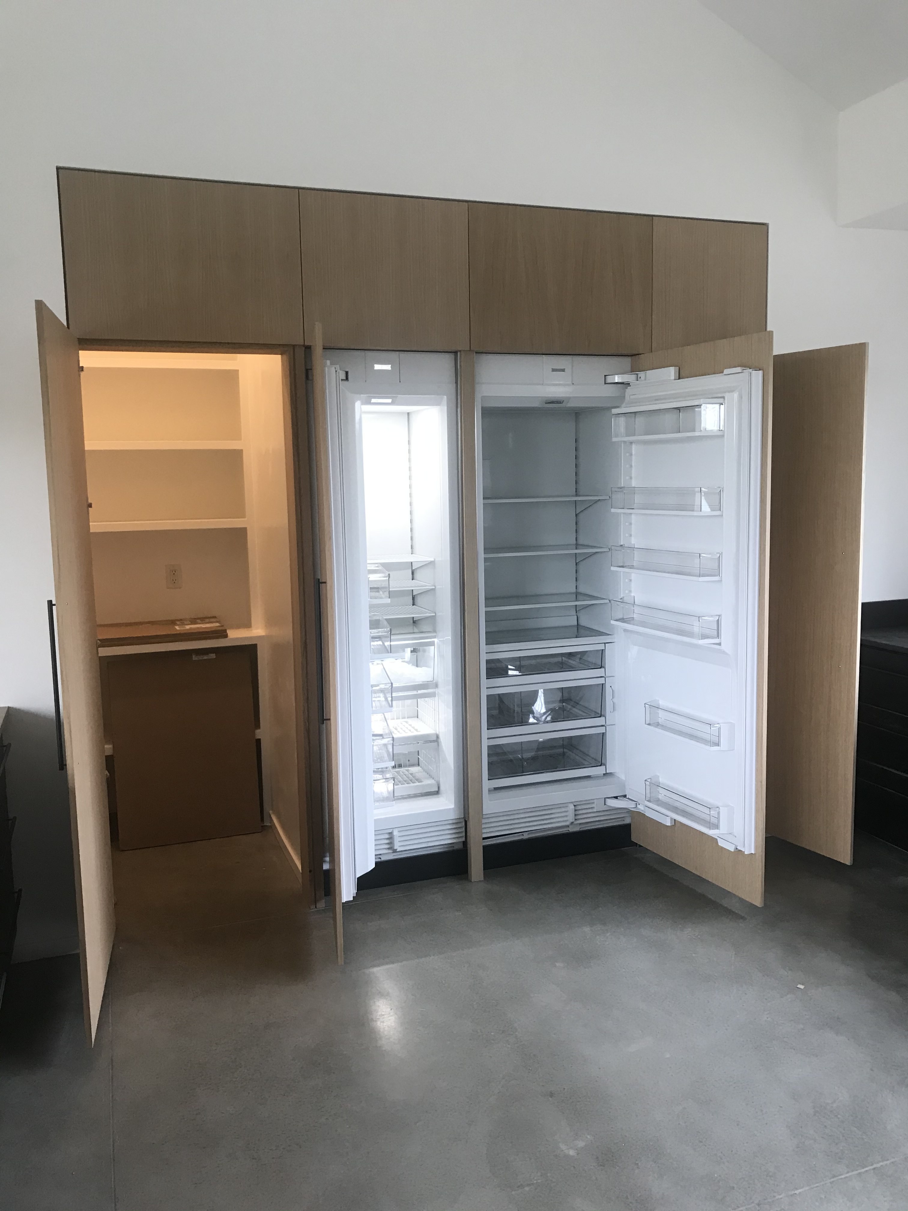 Modern flat-panel light wood hidden door swung open, revealing the room and built-in shelving behind it
