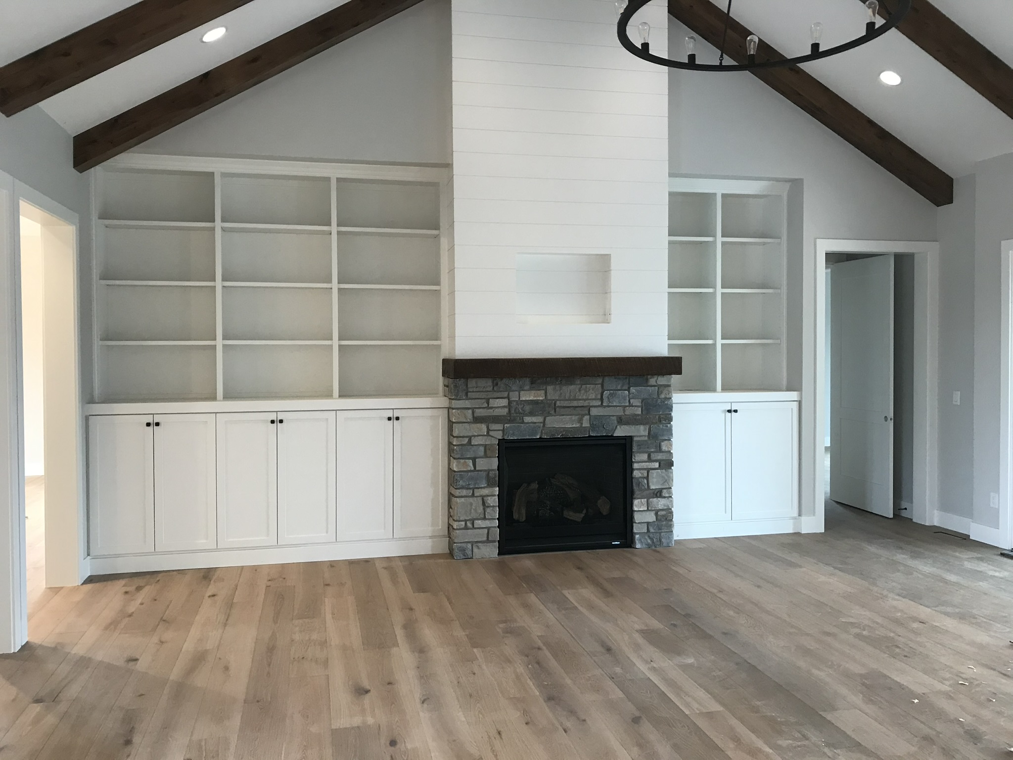 Symmetrical white painted built-in shelving flanking a fireplace with custom mantel surround