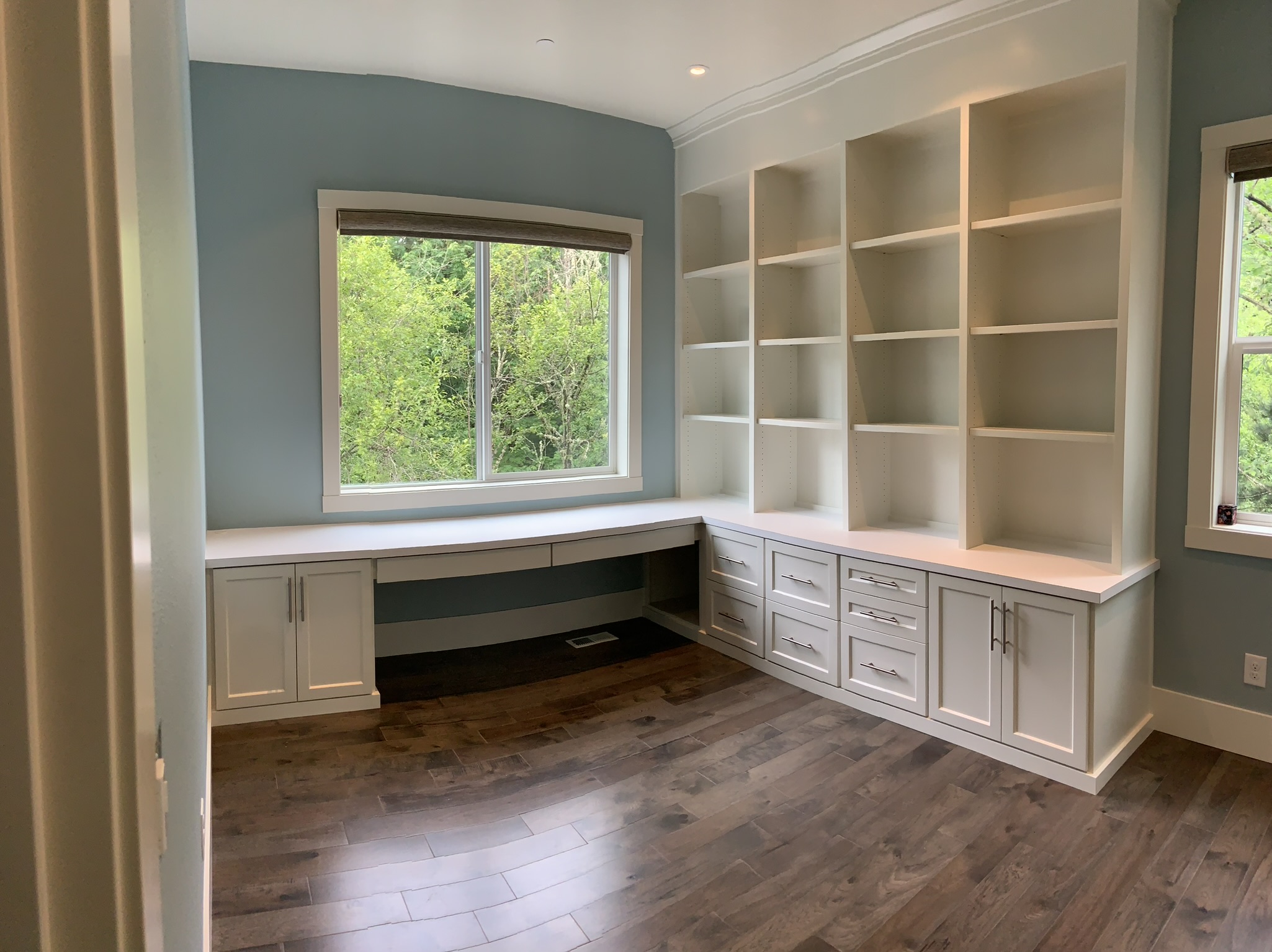 Custom built-in white home office with desk, base cabinets, and cubby shelving