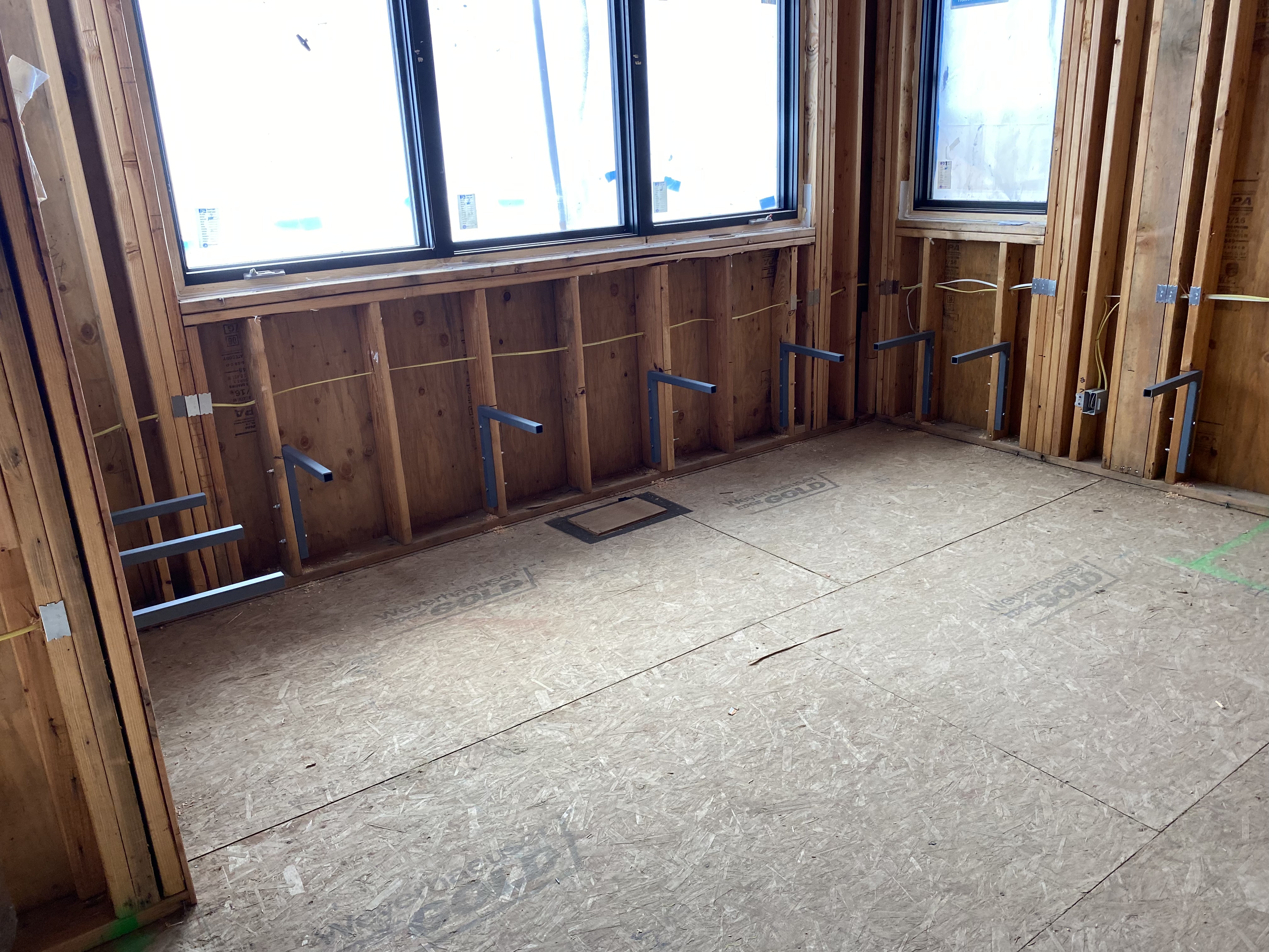 Rough framing of built-in banquette nook under windows, showing steel bracket blocking before finish work