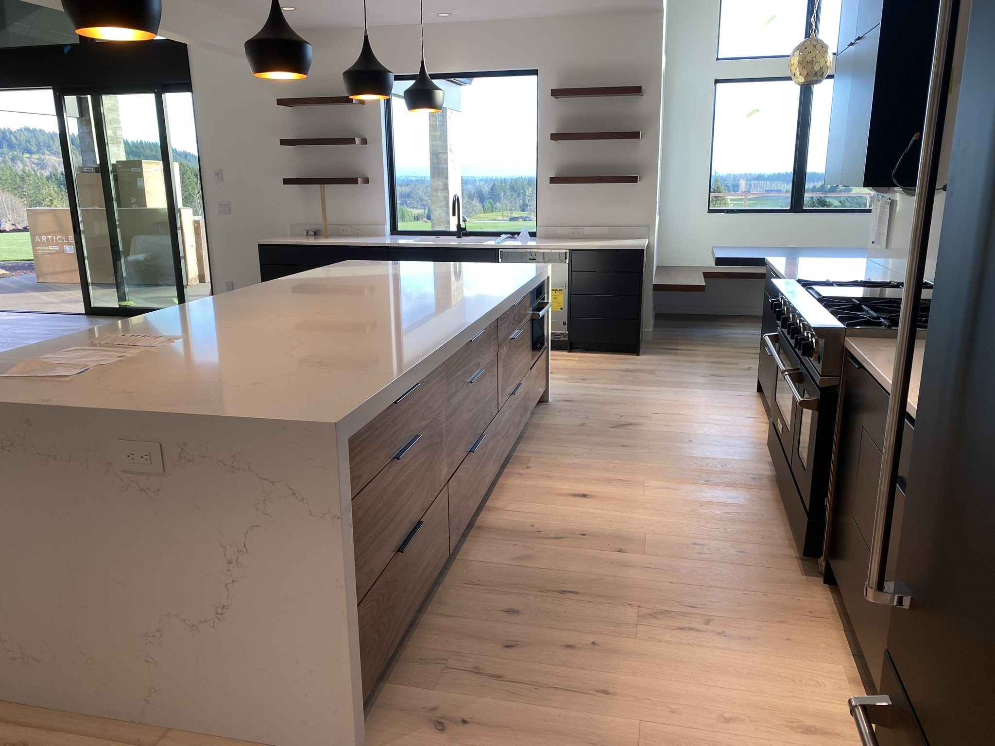Modern kitchen with matte black lower cabinets and walnut upper fronts, featuring a waterfall island