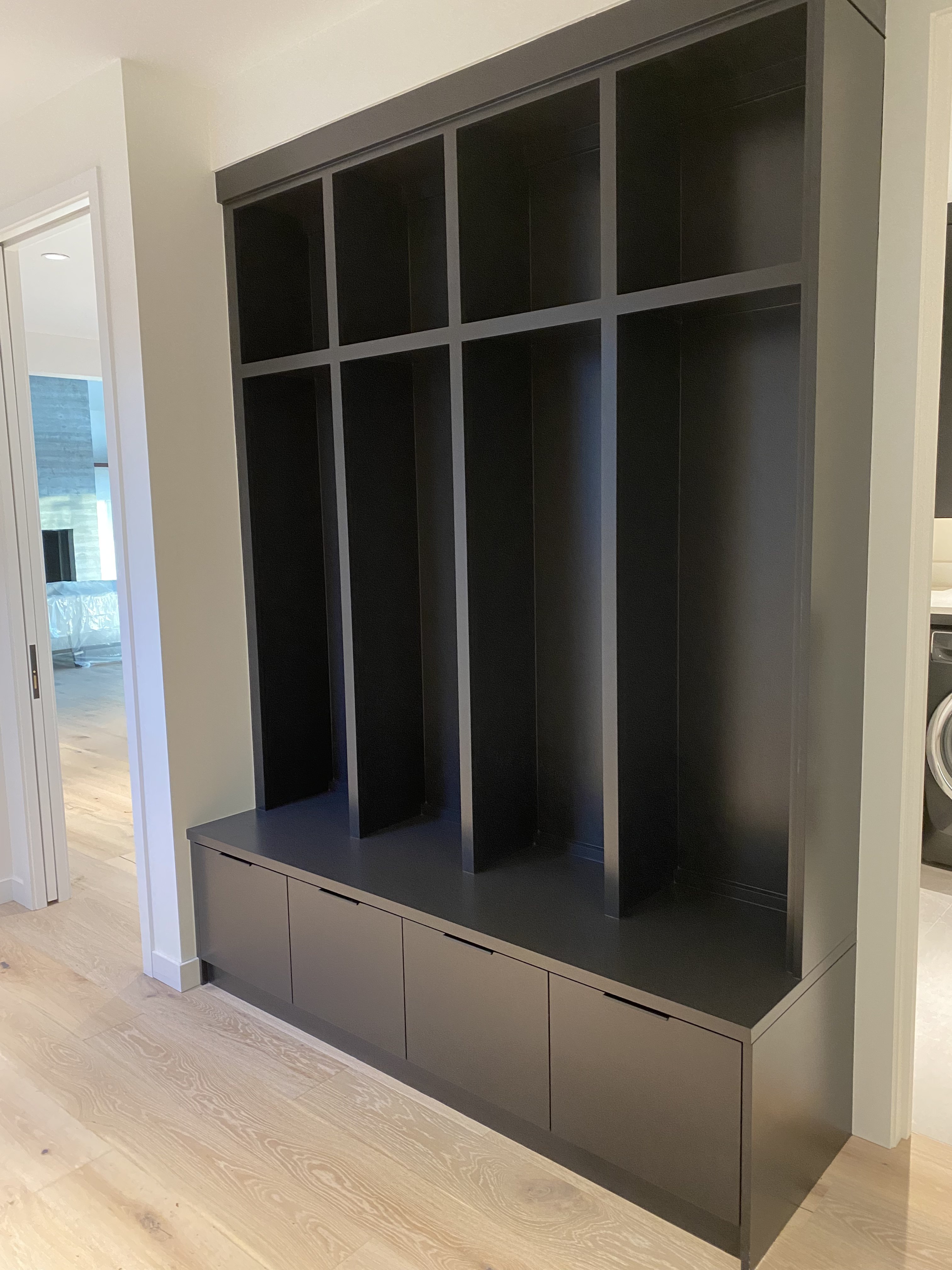 Matte black built-in shelving unit with open display shelves and integrated drawer column