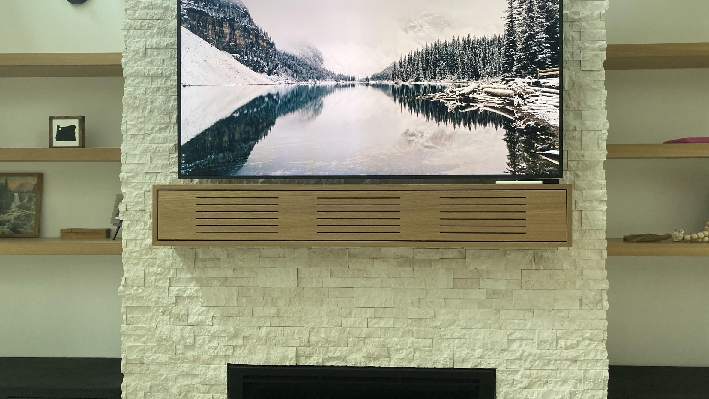 Custom media mantle on stone fireplace concealing AV equipment