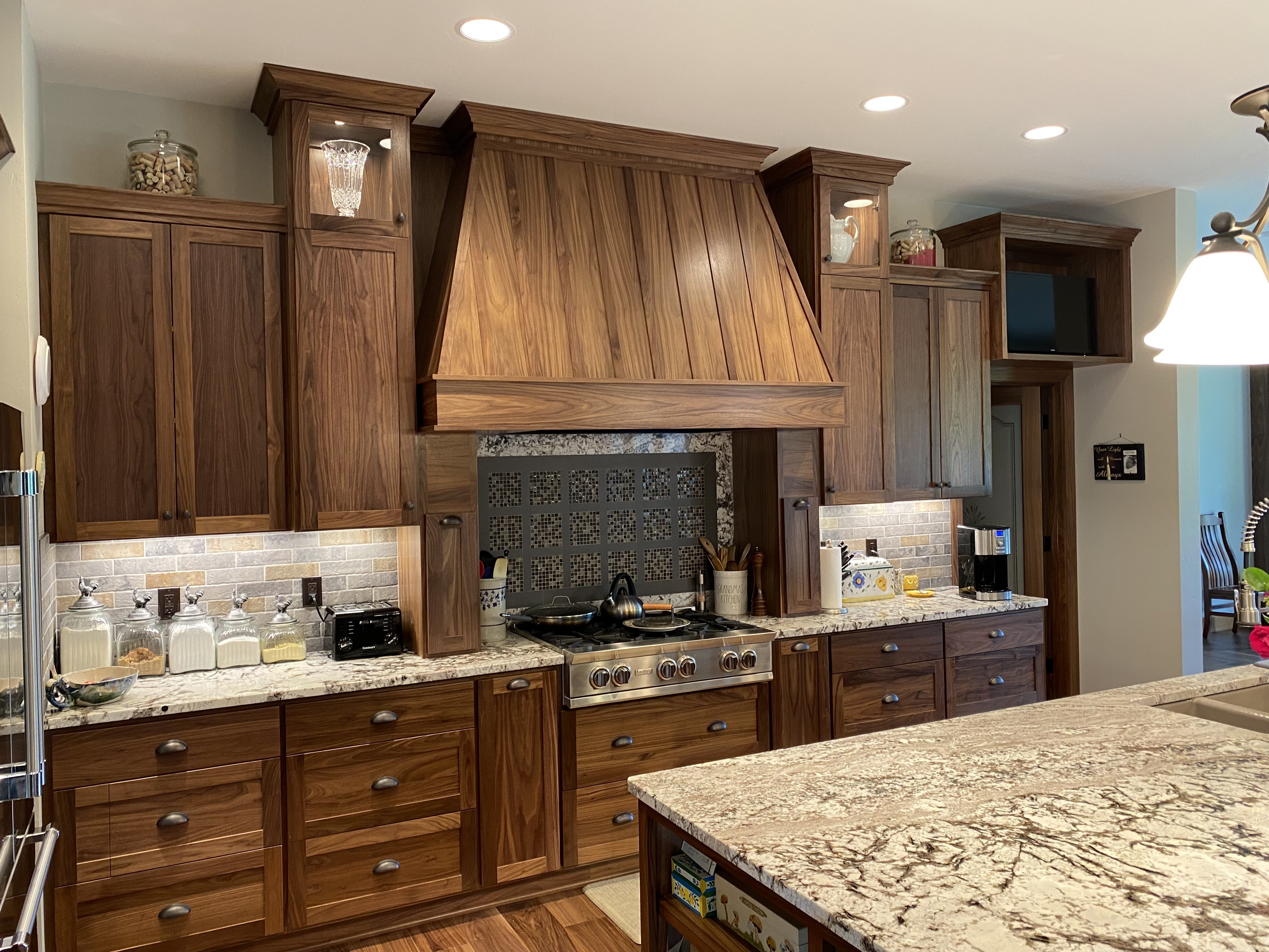 Traditional walnut kitchen with custom range hood, glass-front upper cabinets, and granite countertops