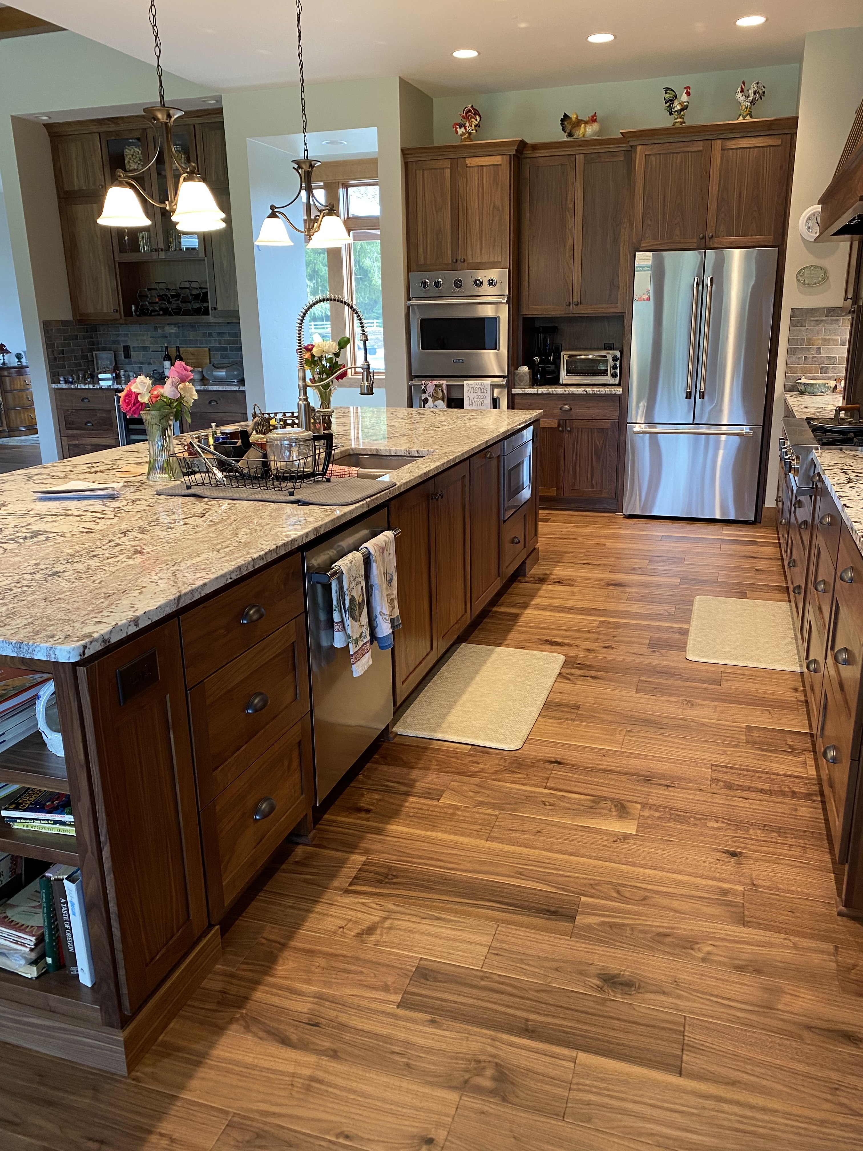 Wide view of traditional walnut kitchen showing island, stainless appliances, and hardwood floors