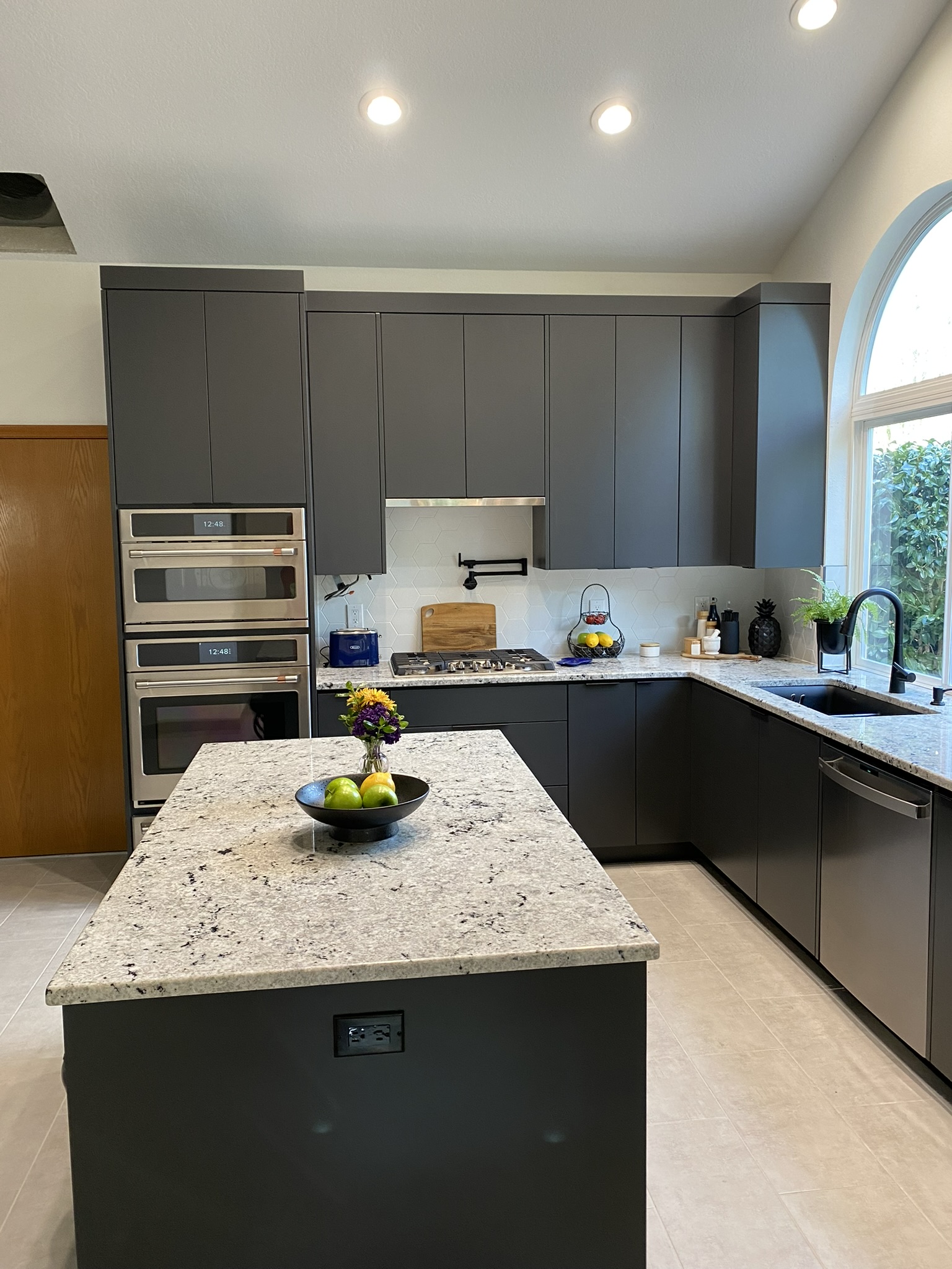 Full kitchen view with flat-panel charcoal gray slab cabinetry and integrated appliances