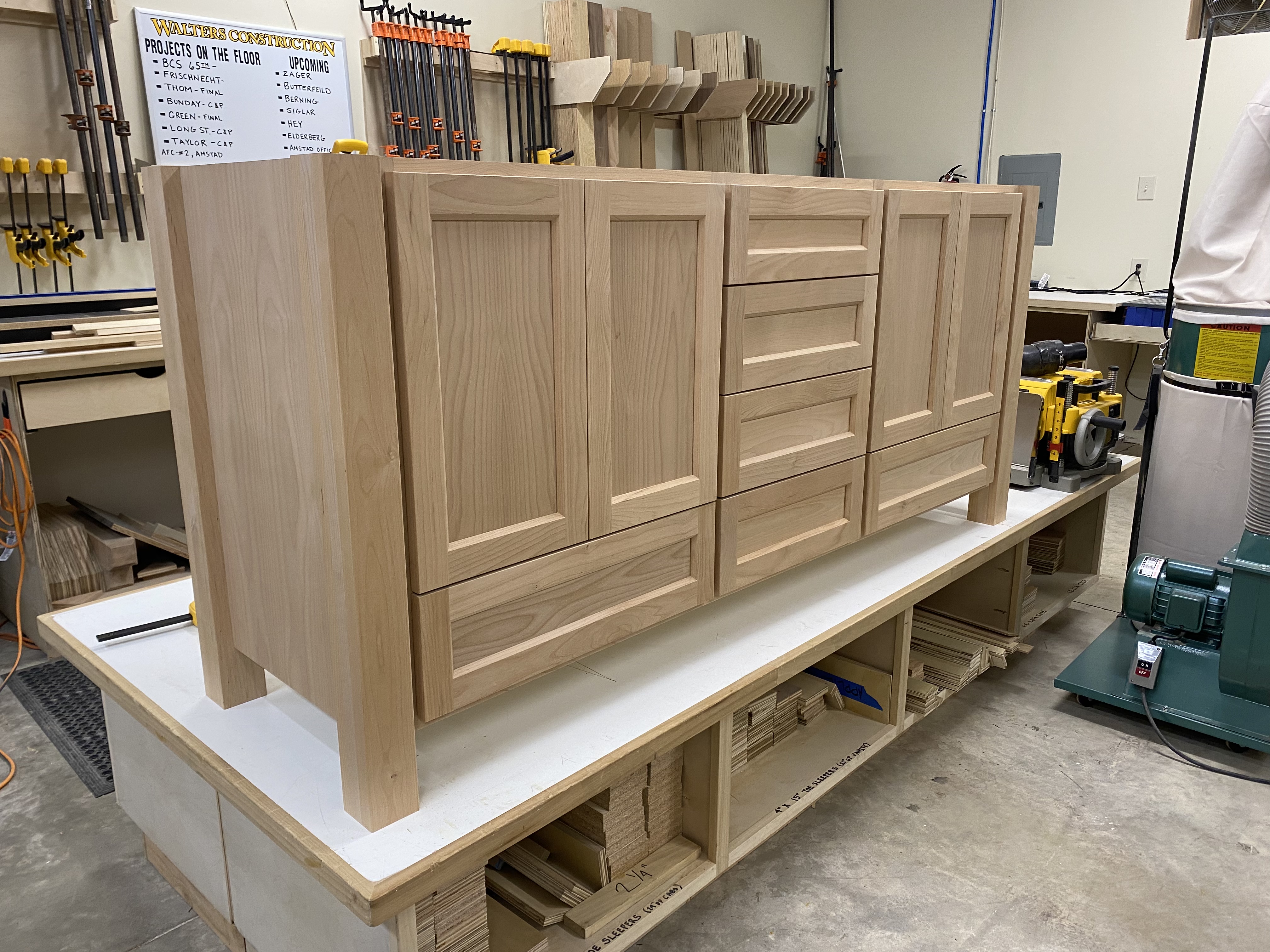 Wide unfinished oak double vanity with raised-panel doors and center drawer bank fresh from the shop